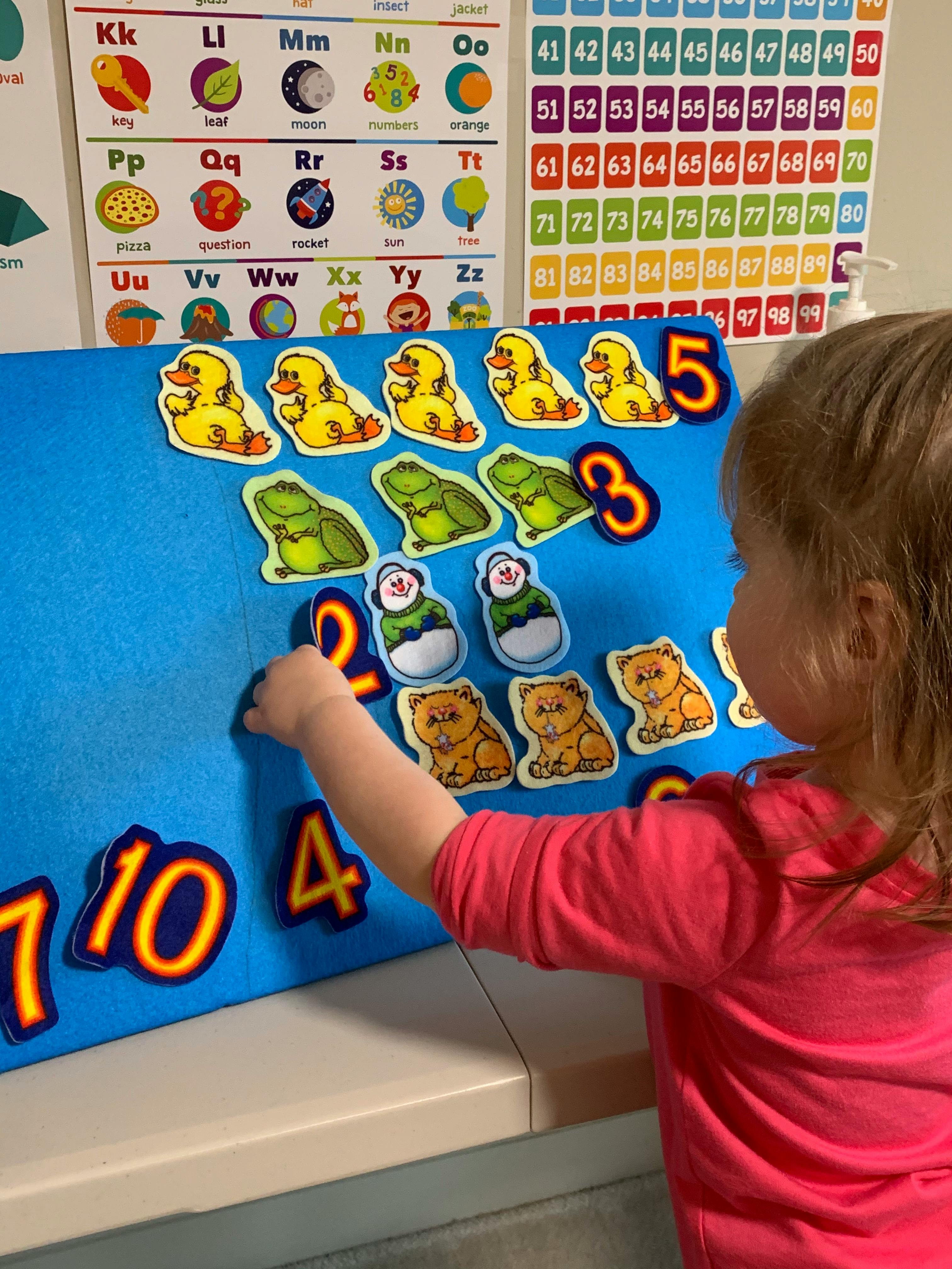 Child playing with number and animal cutouts on a blue board
