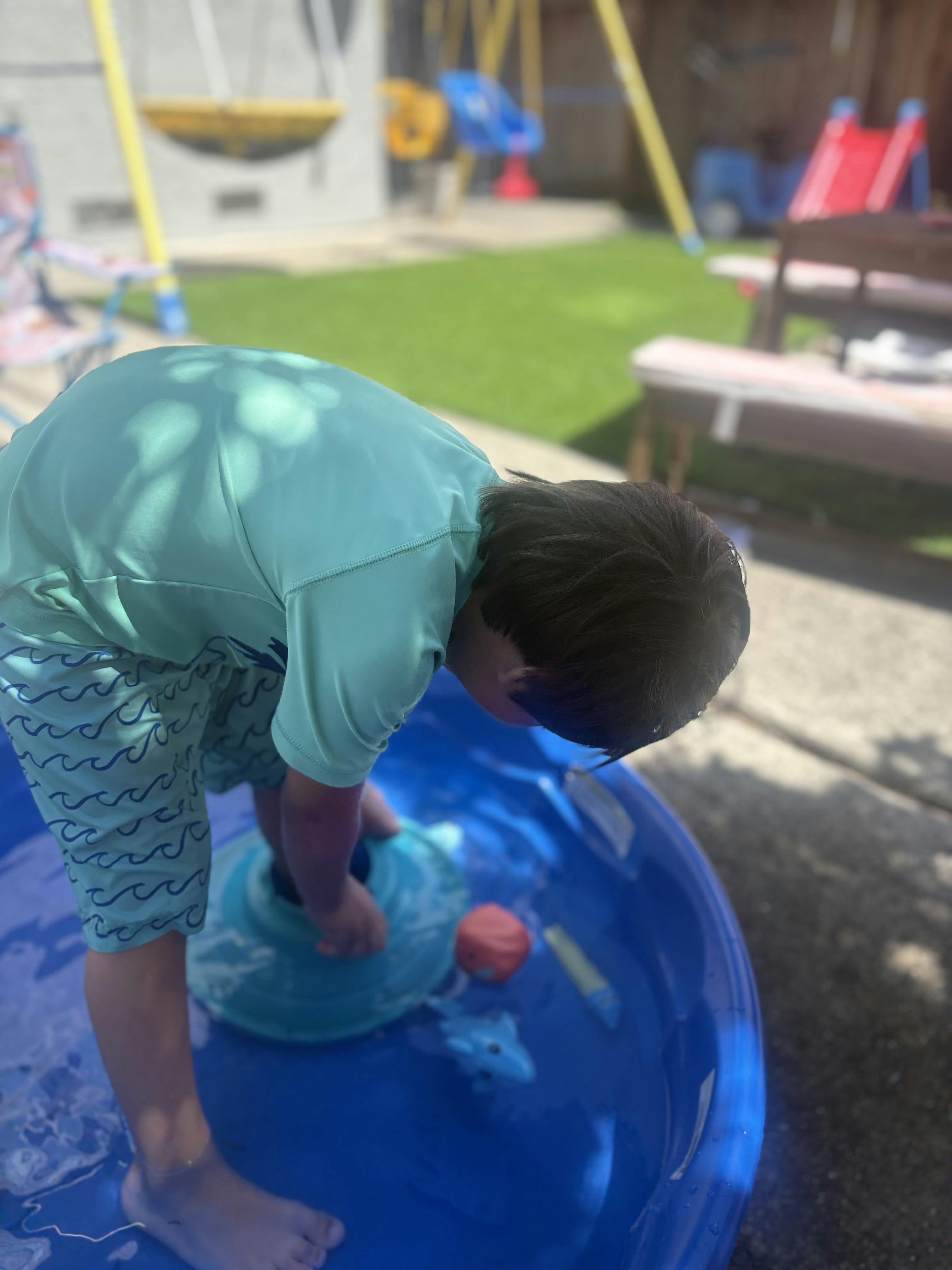 Child playing in a small blue plastic pool