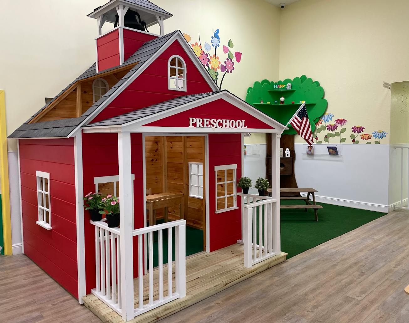 Red playhouse school building with a small bell tower and a sign that says "PRESCHOOL"