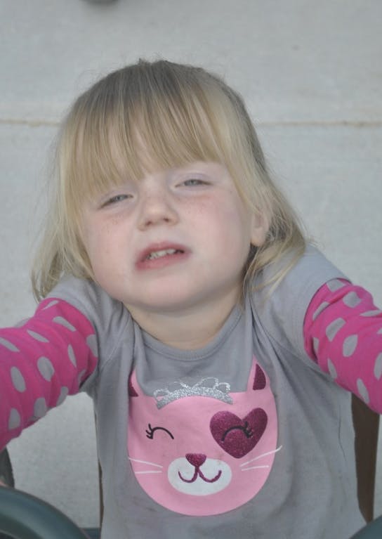 Child with blonde hair wearing a gray shirt with a pink cat design