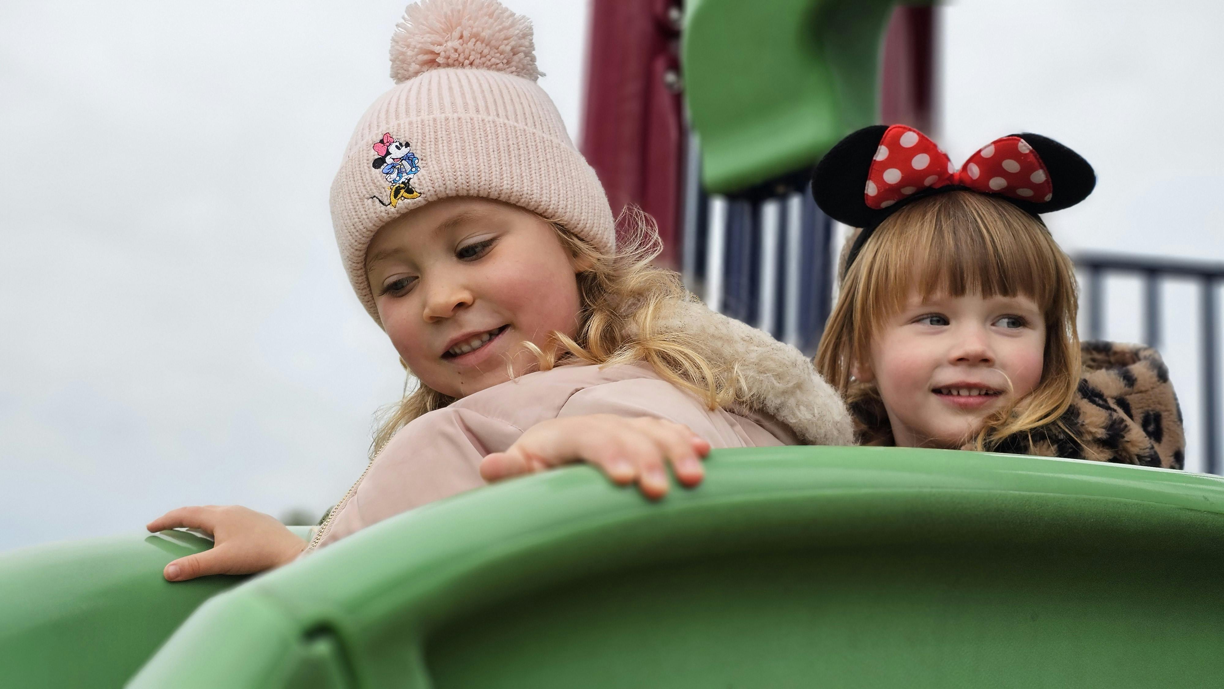 Two children on a green playground slide