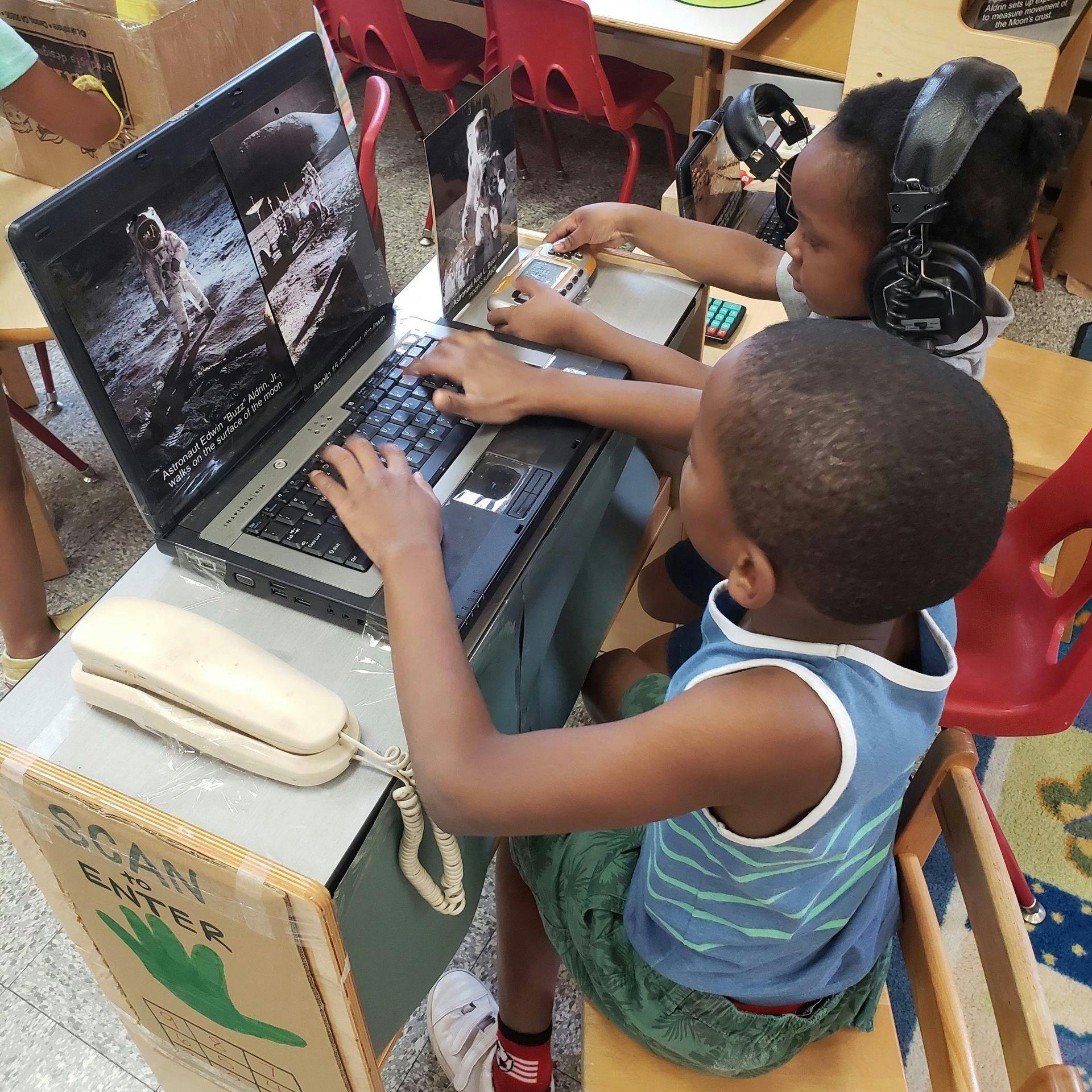 Two children using laptops in a classroom
