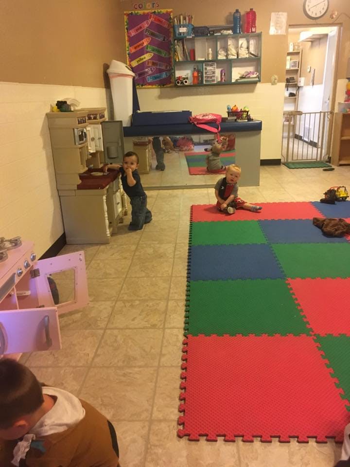 Two children playing in a room with a colorful mat
