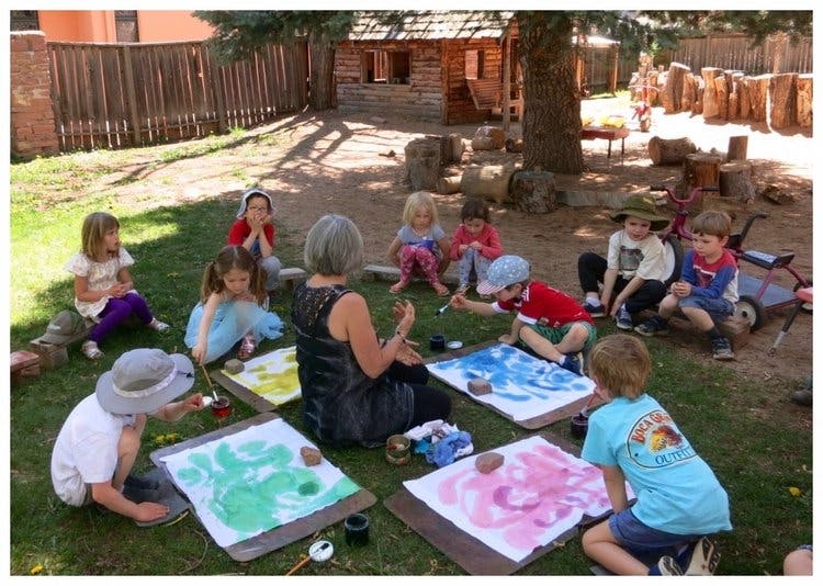 Adult and children painting on canvases outdoors