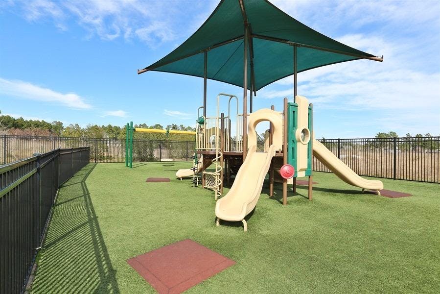 Playground with slides and climbing structure under a shade canopy