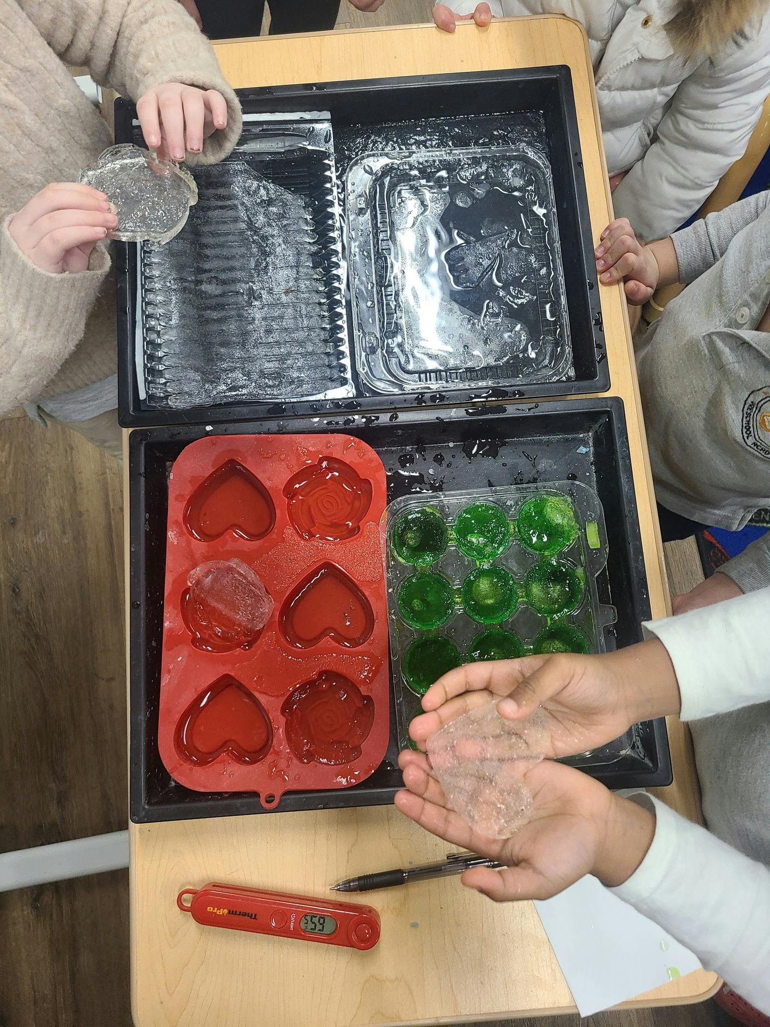 Children's hands playing with ice in various molds
