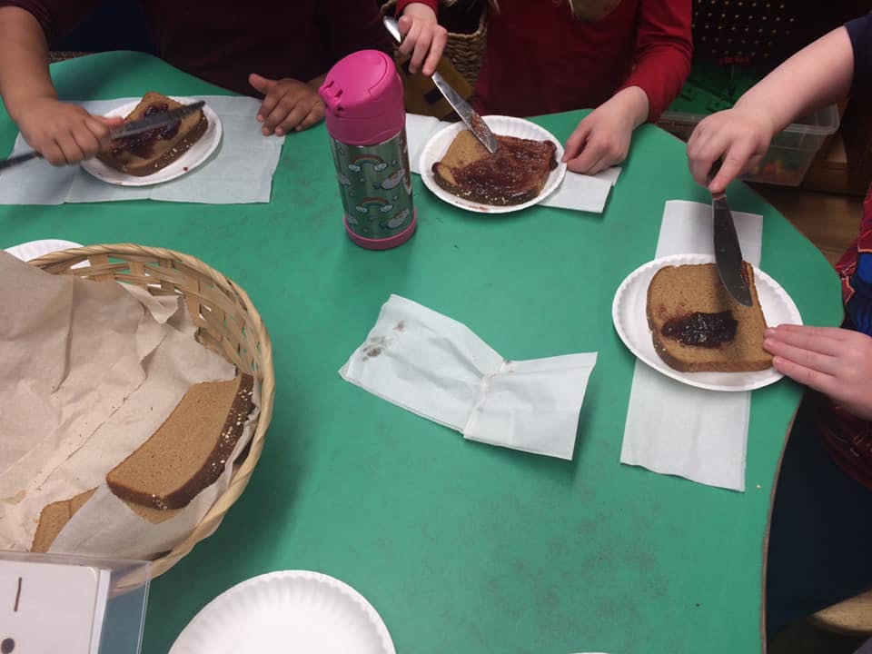 People spreading jam and peanut butter on bread