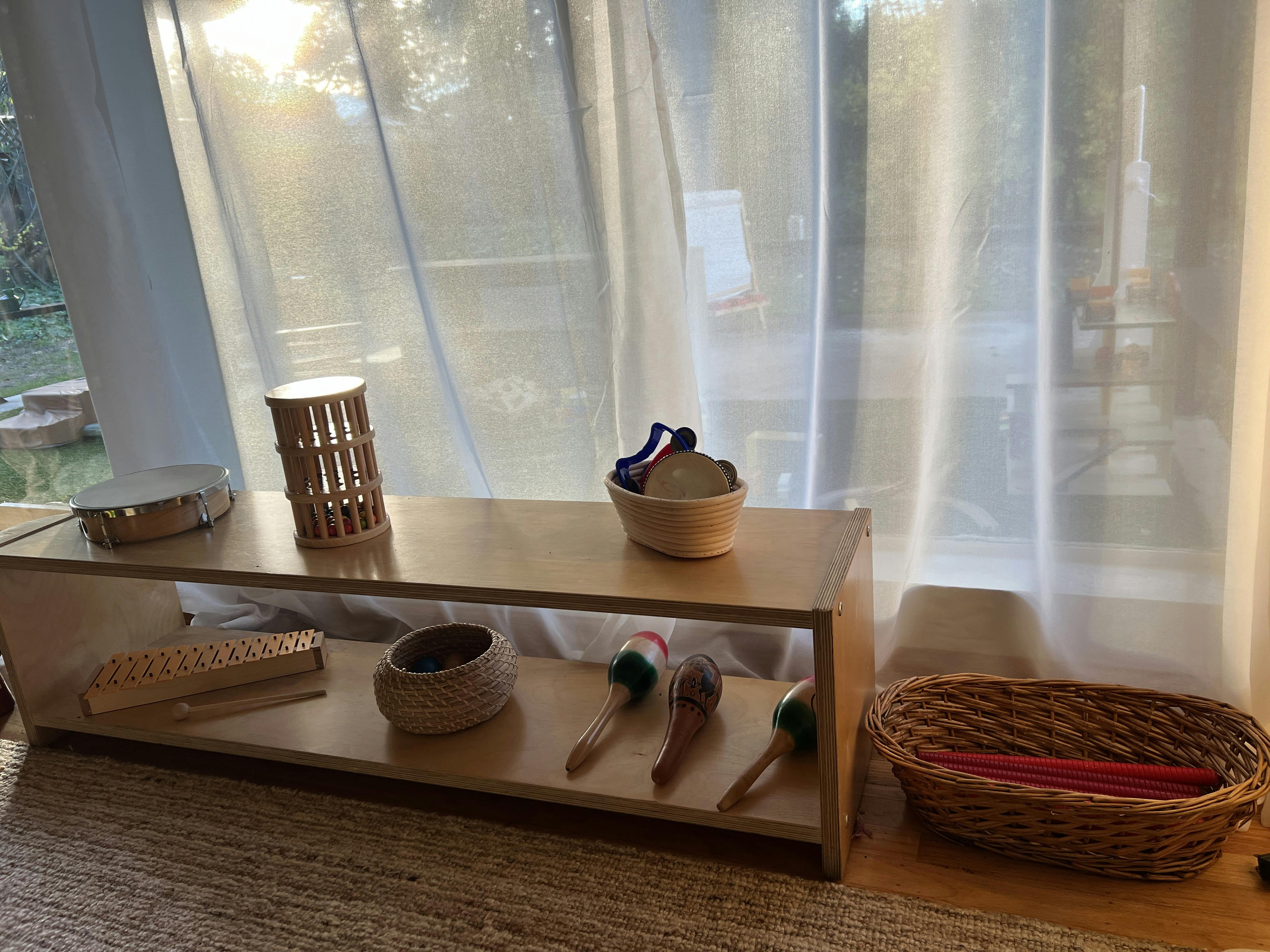 Wooden shelf with various musical instruments like a tambourine, maracas, and xylophone
