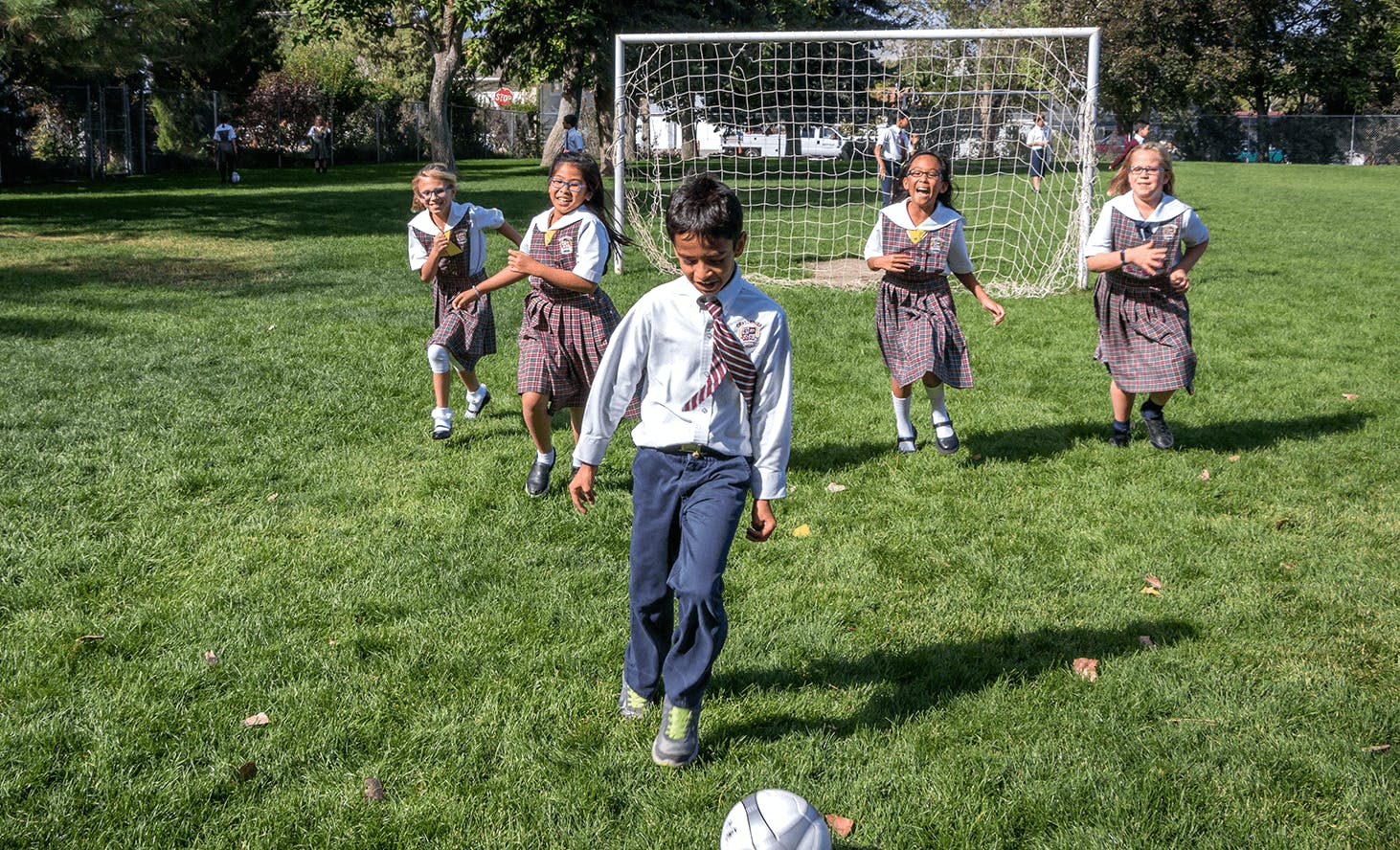 Child playing soccer with other children on a field