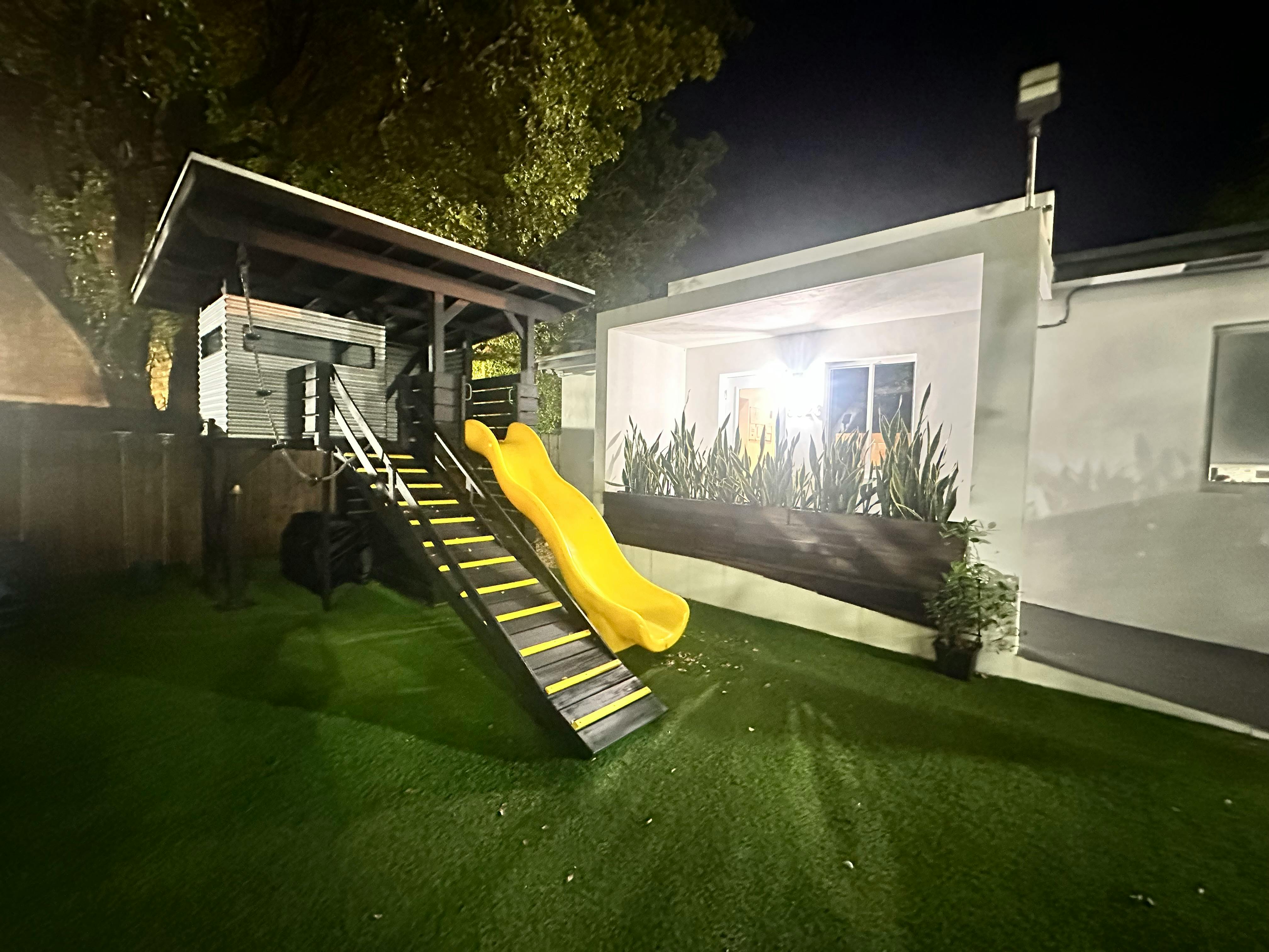 Play structure with a yellow slide and stairs on green turf