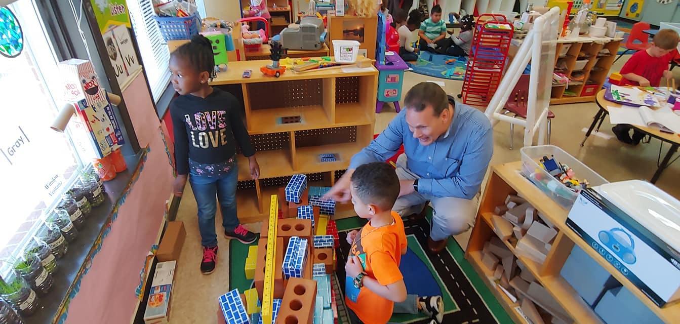 Adult and two children playing with blocks in a classroom