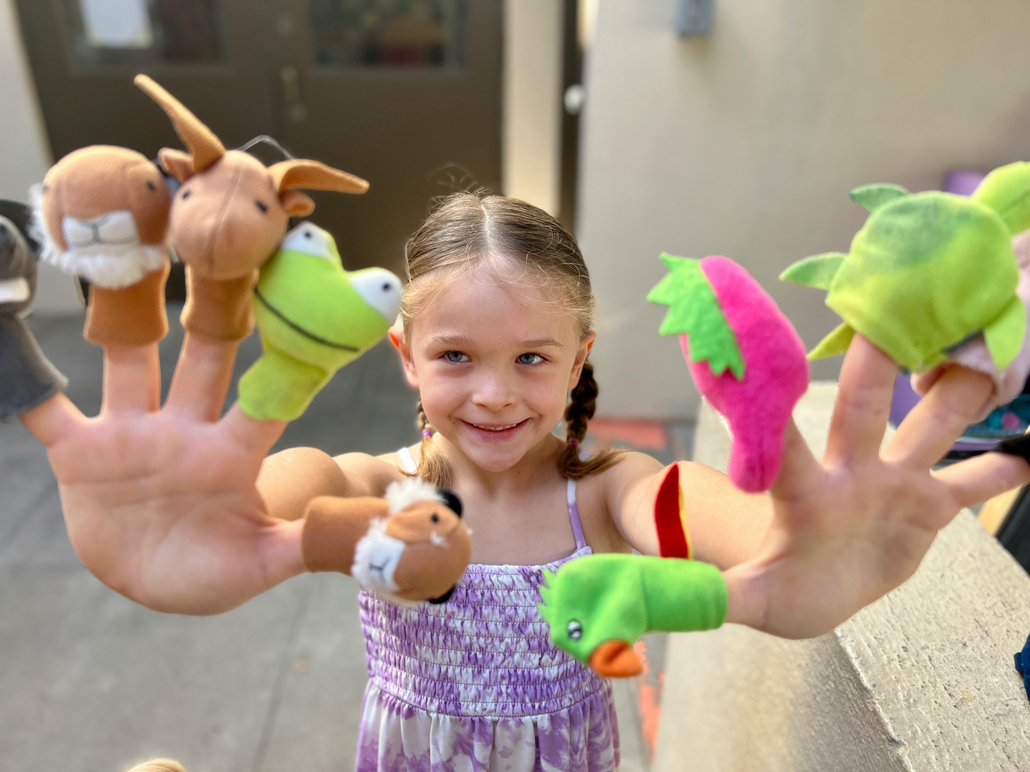 Child with finger puppets on both hands