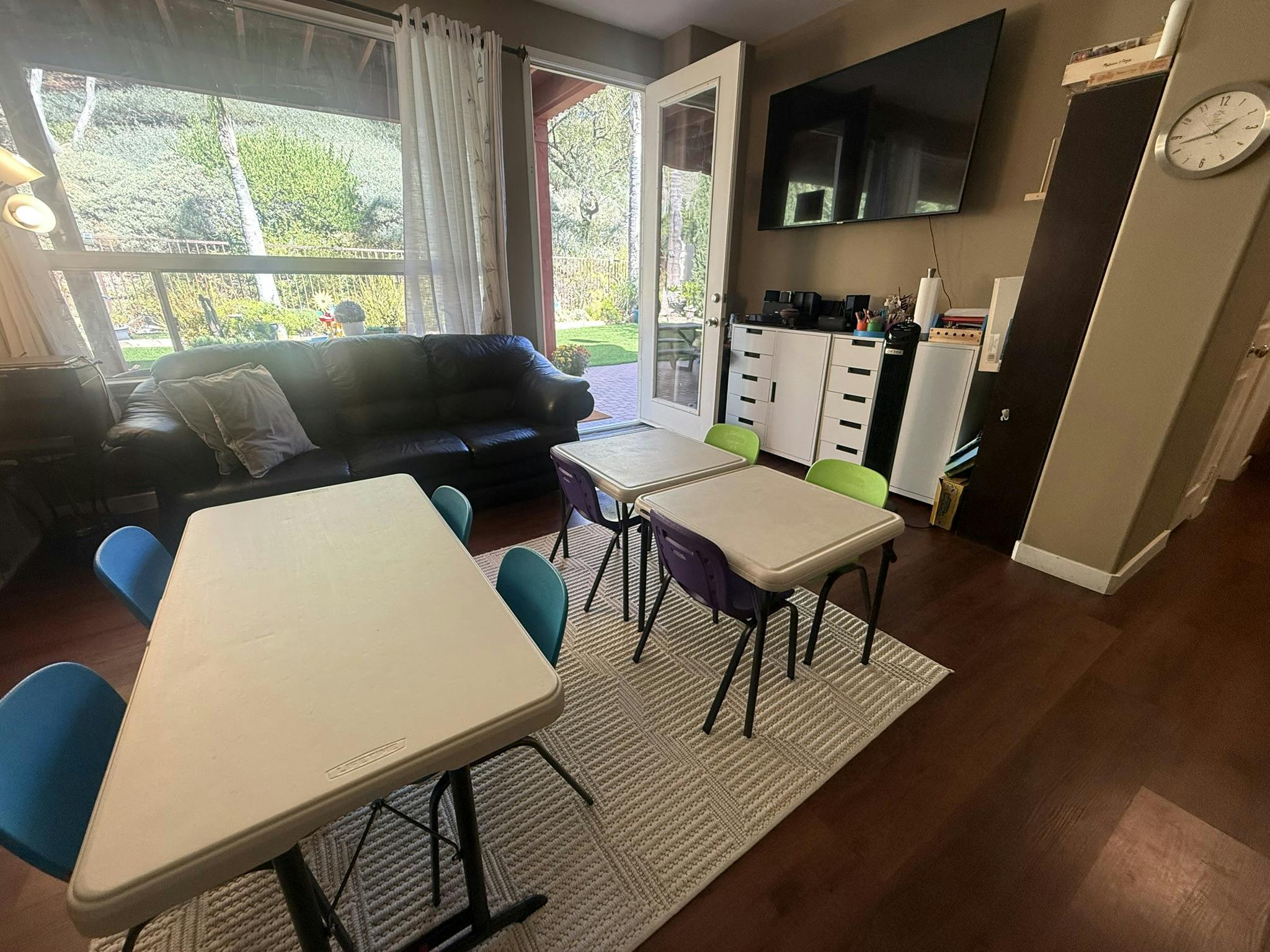 Classroom with multiple tables and chairs, a sofa, and a large window