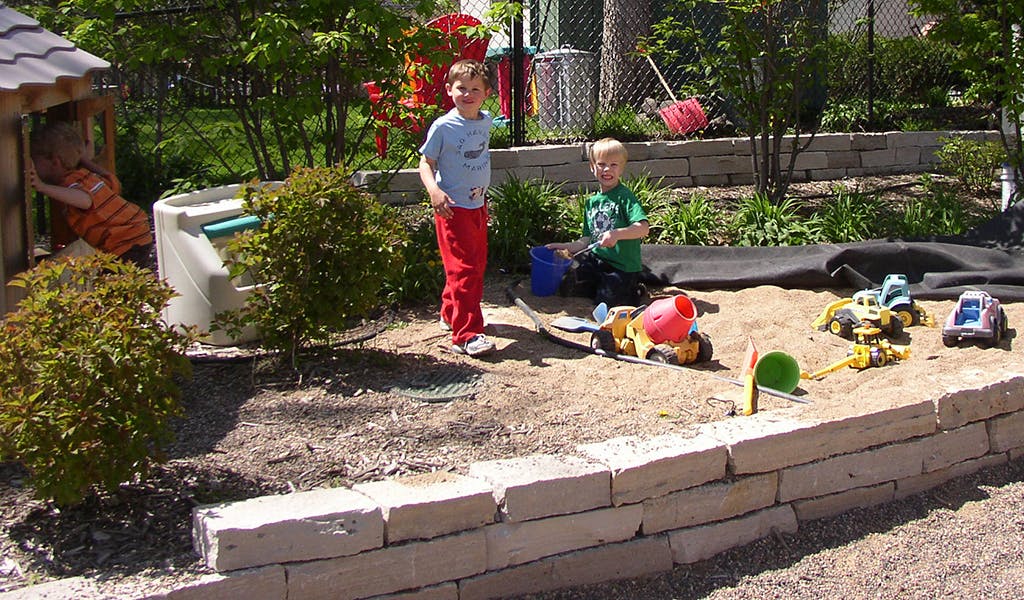 Children playing in a sandbox with toys