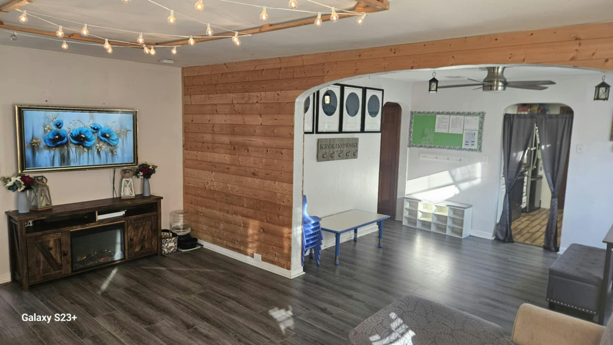 Living room with a TV, wooden console, and string lights