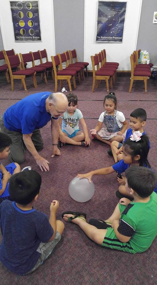 Adult and children sitting on floor in a circle with a balloon