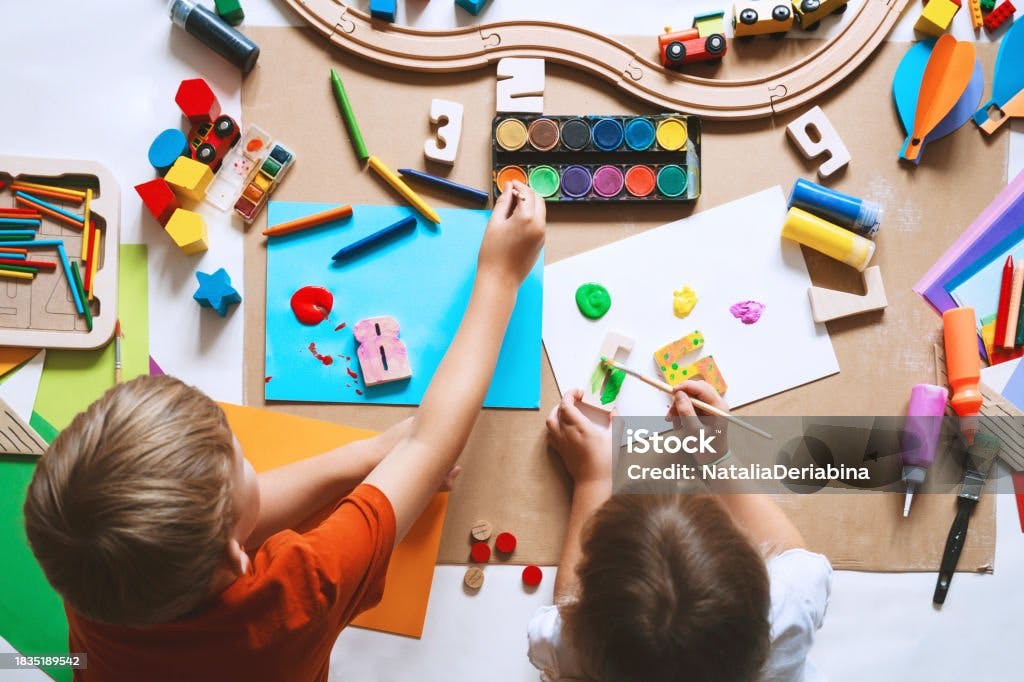 Two children painting and playing with modeling clay