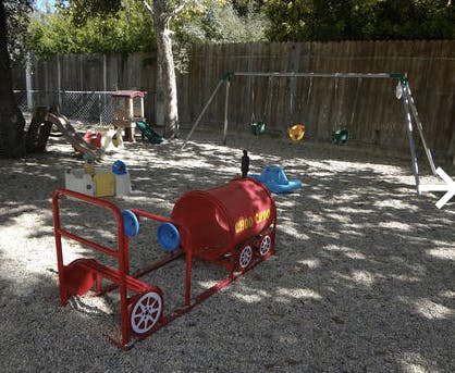 Playground with a red train ride-on toy and swings