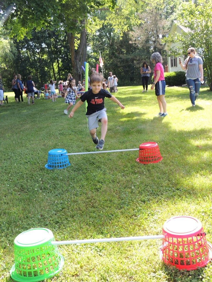 Child jumping over an obstacle in a grassy outdoor area