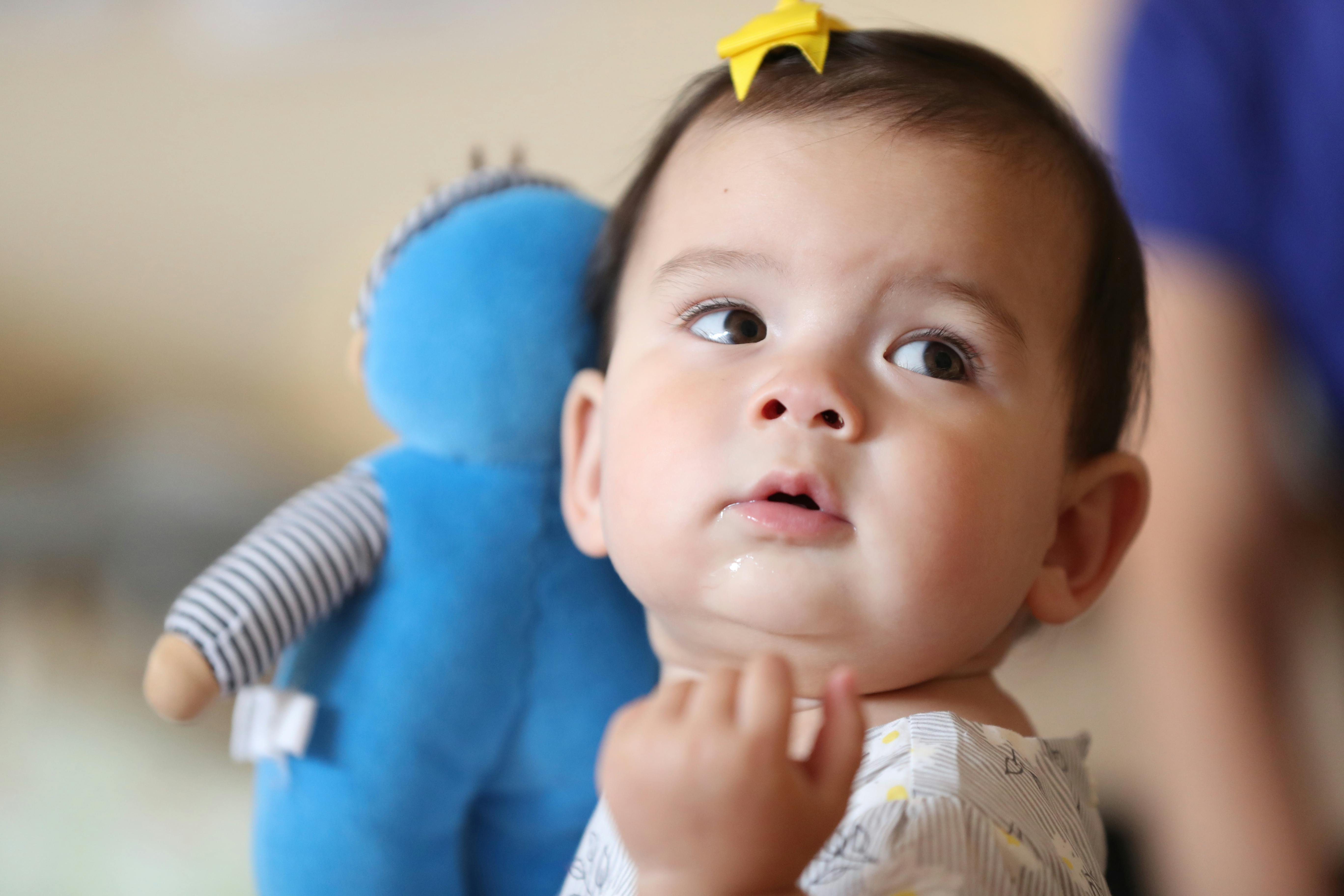 Child with a yellow bow in hair and a blue stuffed animal