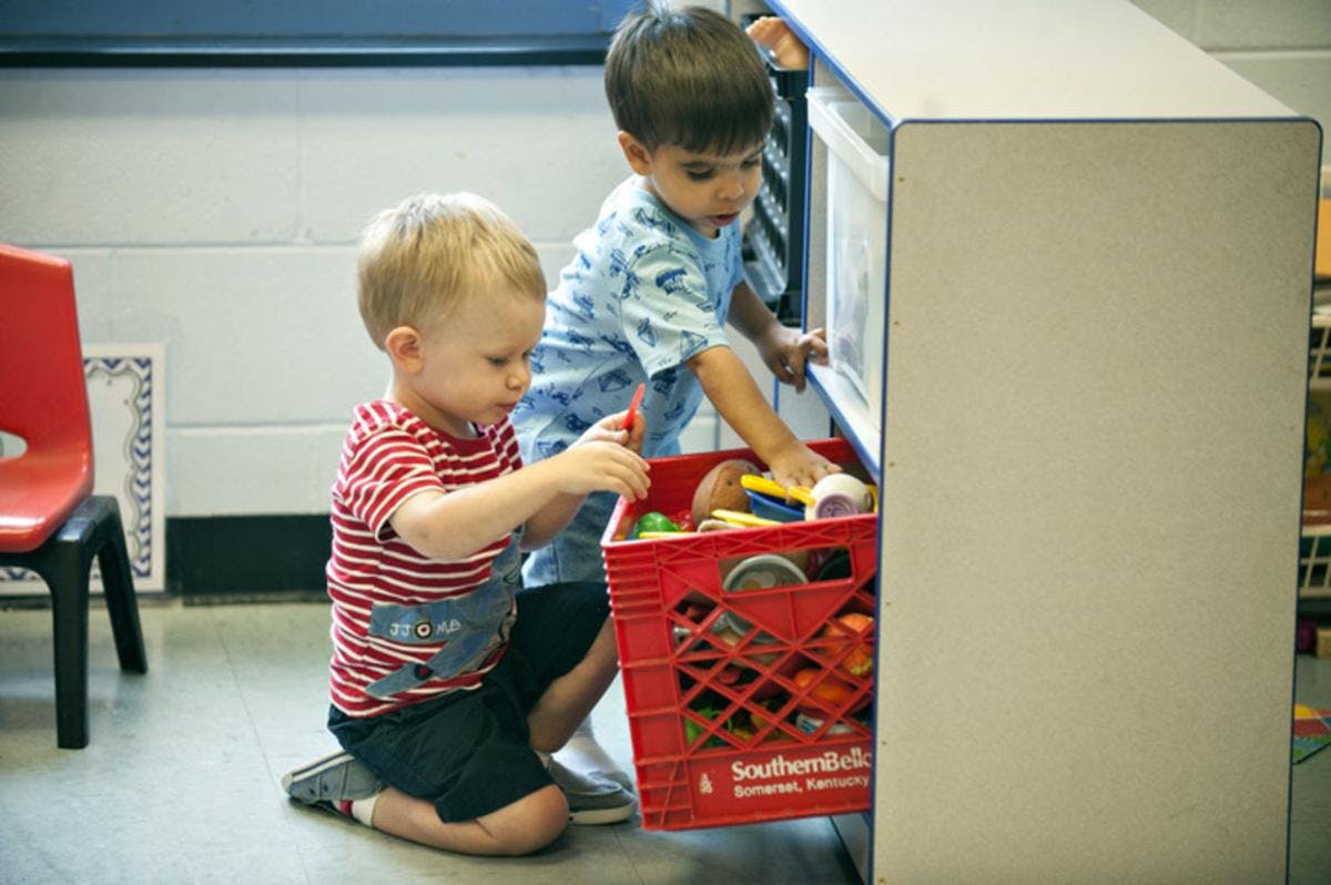 Two children playing with toys in a red crate