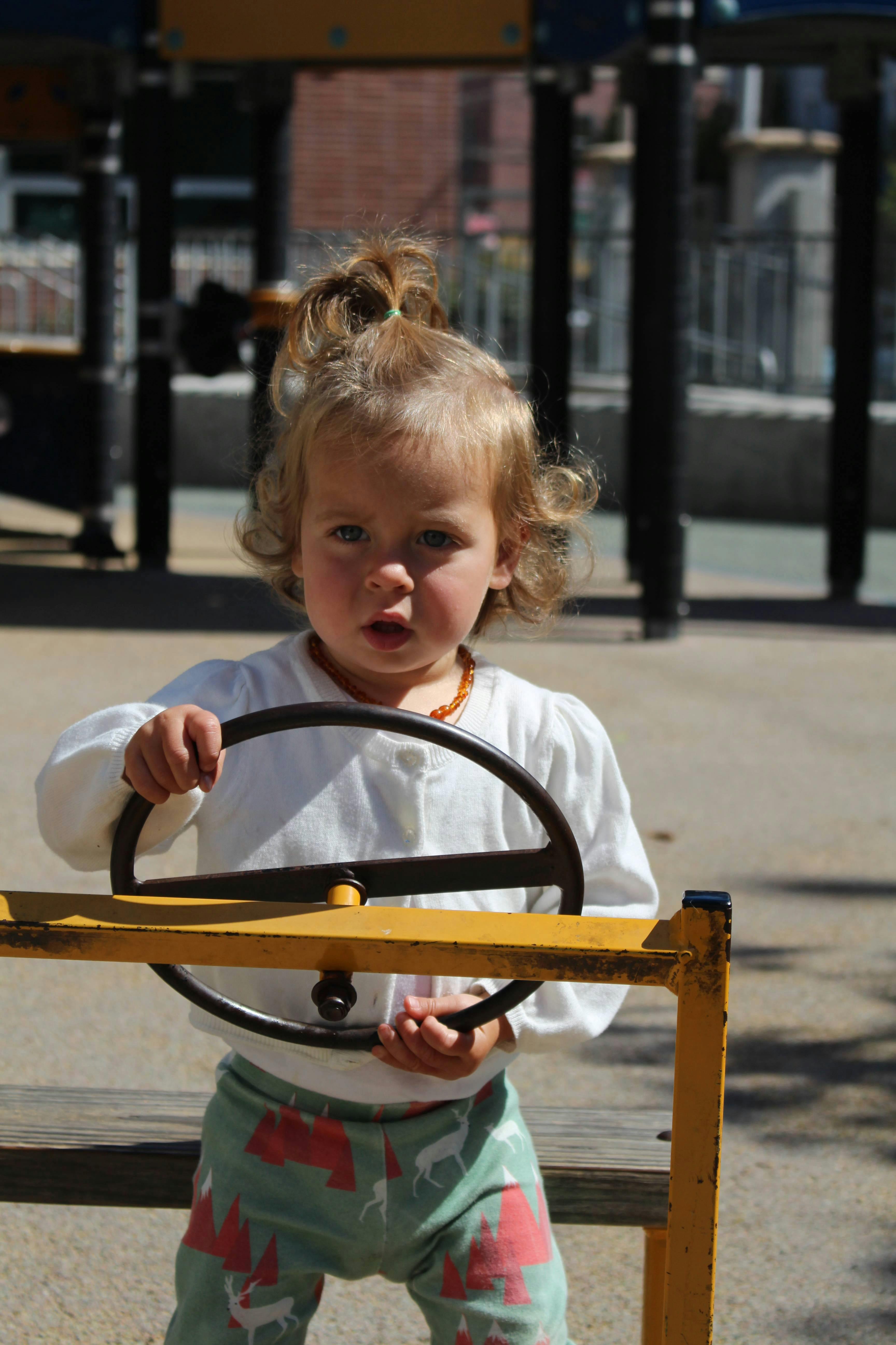 Child holding a steering wheel on a playground