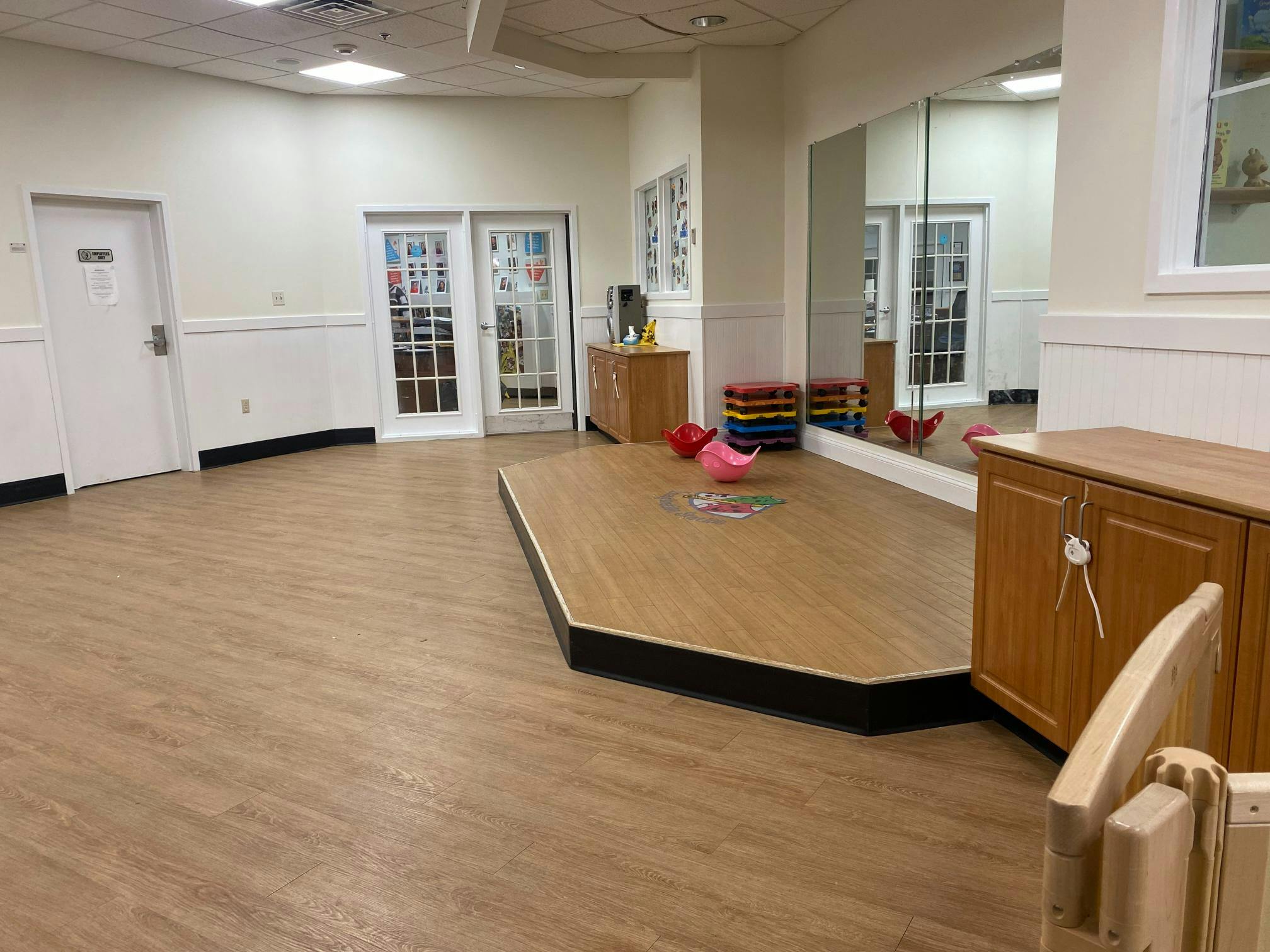 An empty indoor play space with a small stage and mirrors