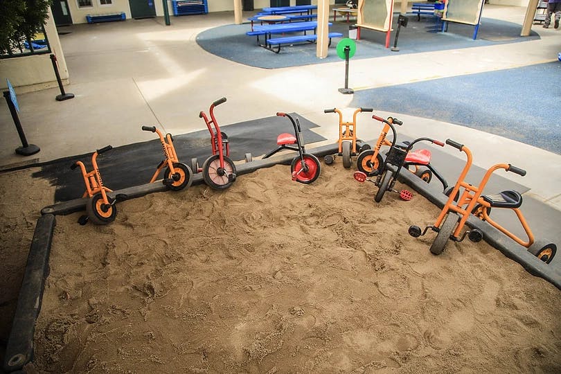 Children's bikes and scooters in a sandbox