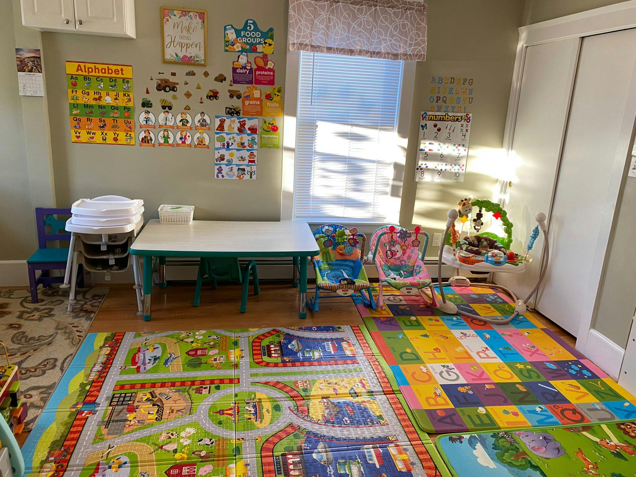 Playroom with colorful mats, small table and chairs, and baby equipment