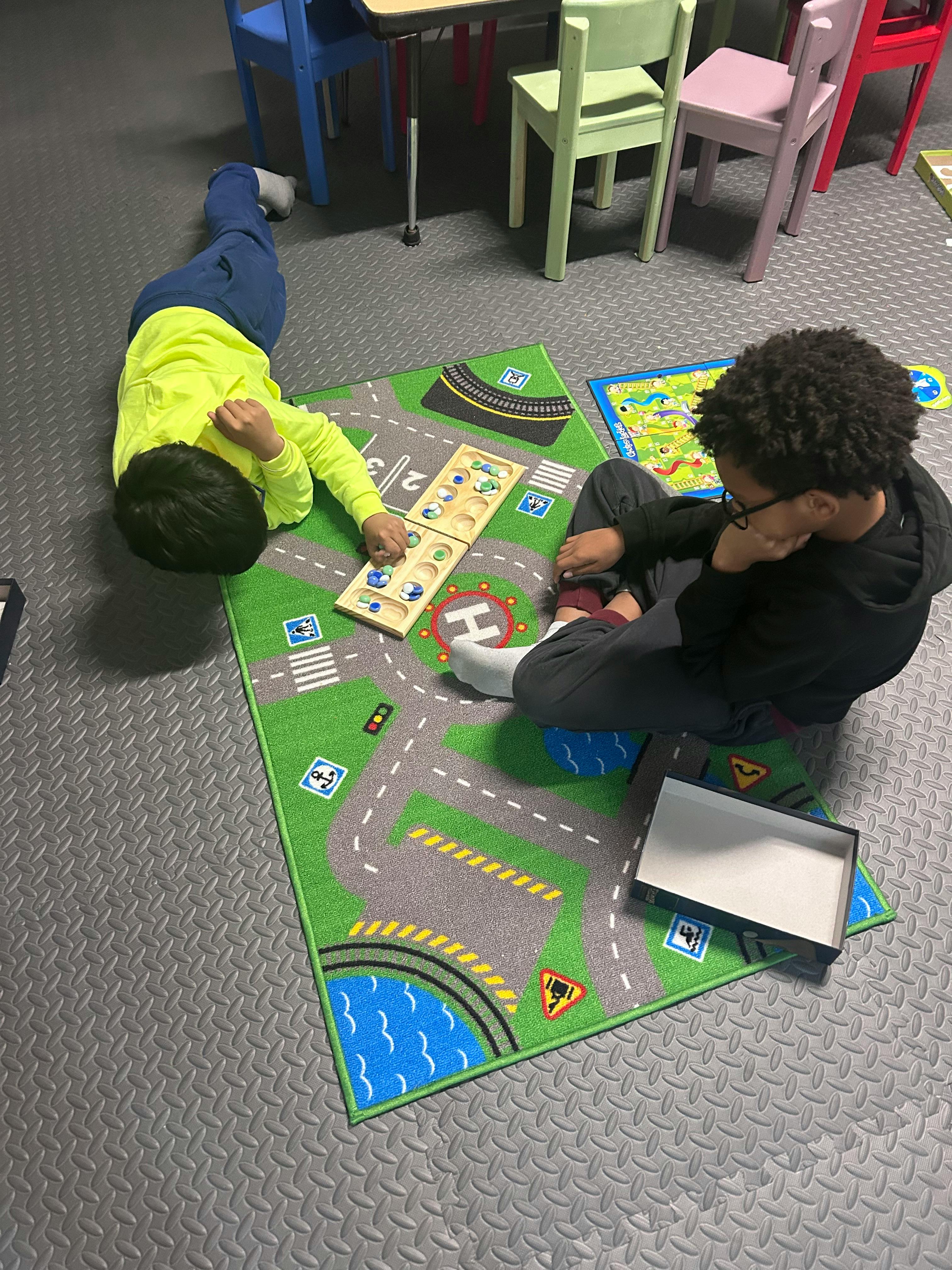 Two children playing on a road-themed rug with a puzzle