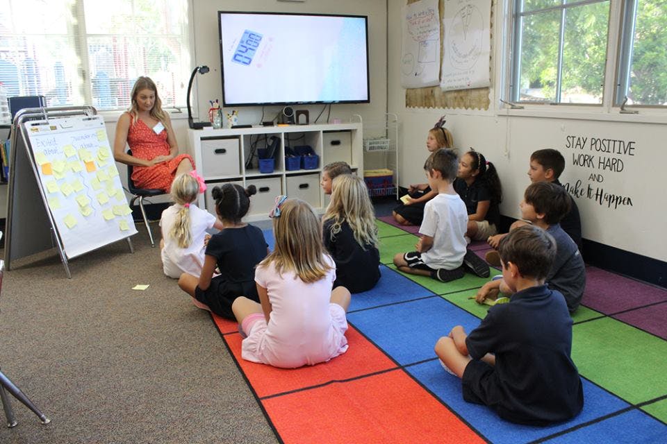 Adult and children sitting on floor in classroom