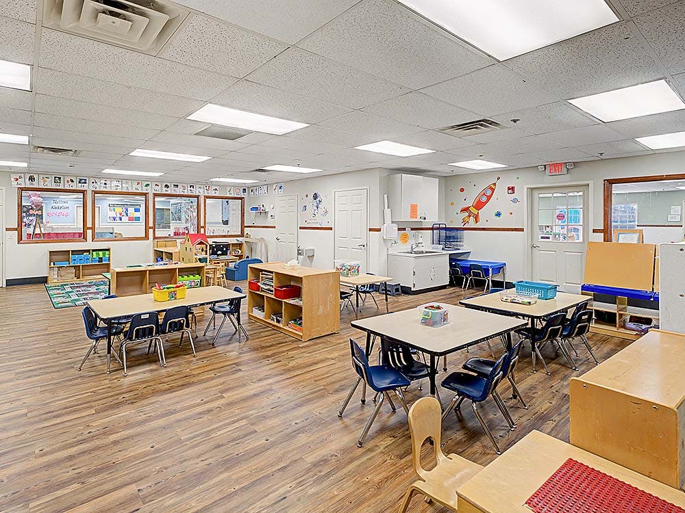 Empty colorful preschool classroom with small tables and chairs