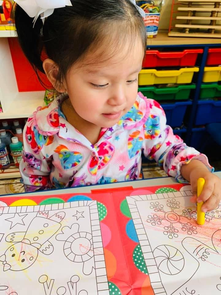 Child coloring a picture with a yellow crayon