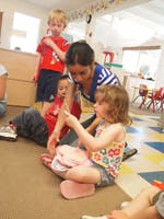 Adult and three children interacting in a classroom