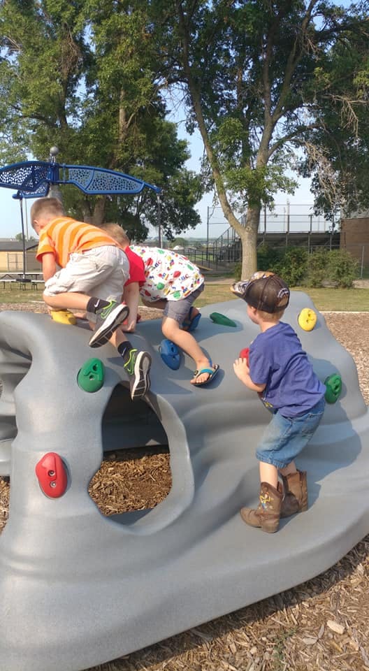 Children climbing on a playground rock wall structure