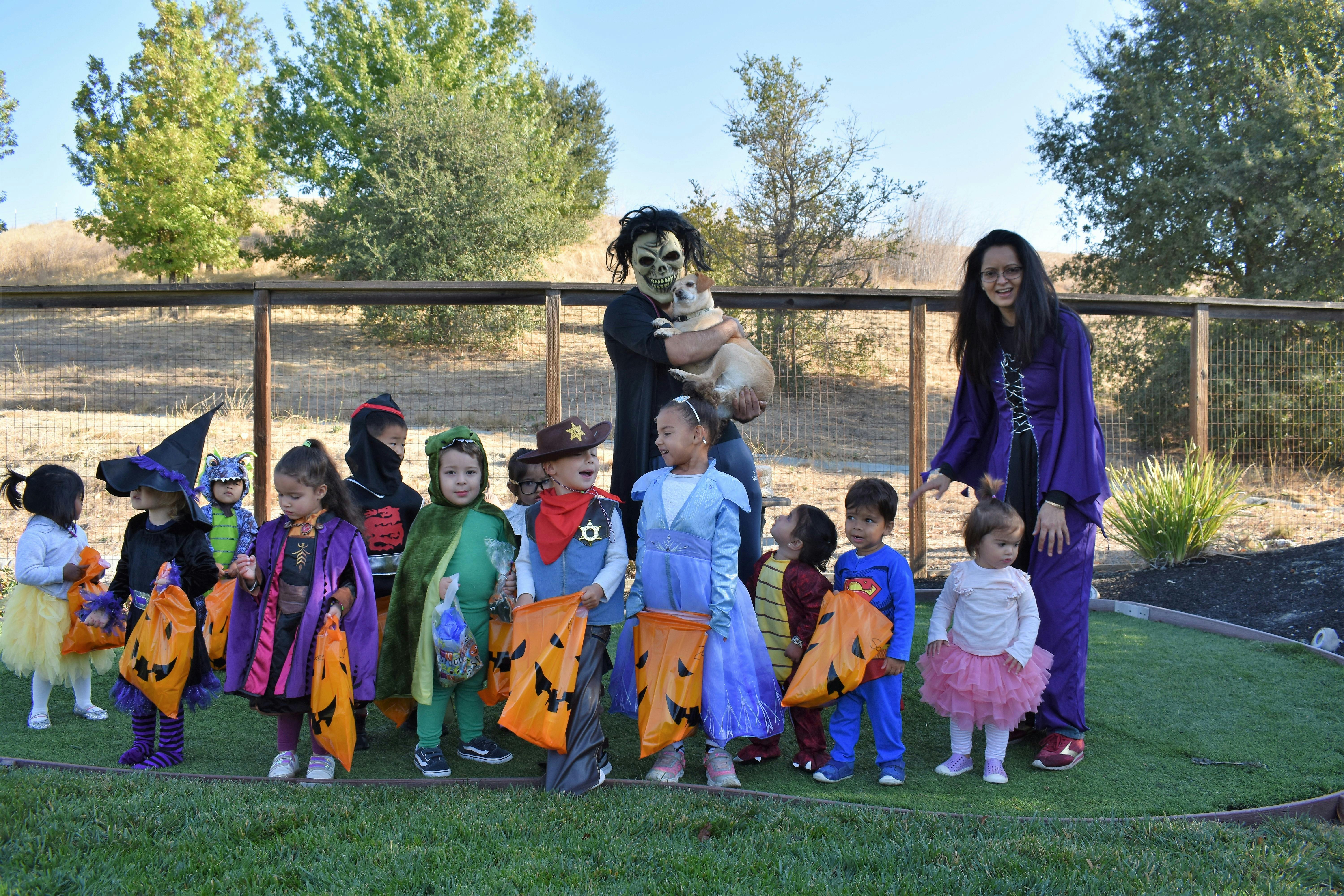 People and children in costumes holding trick-or-treat bags