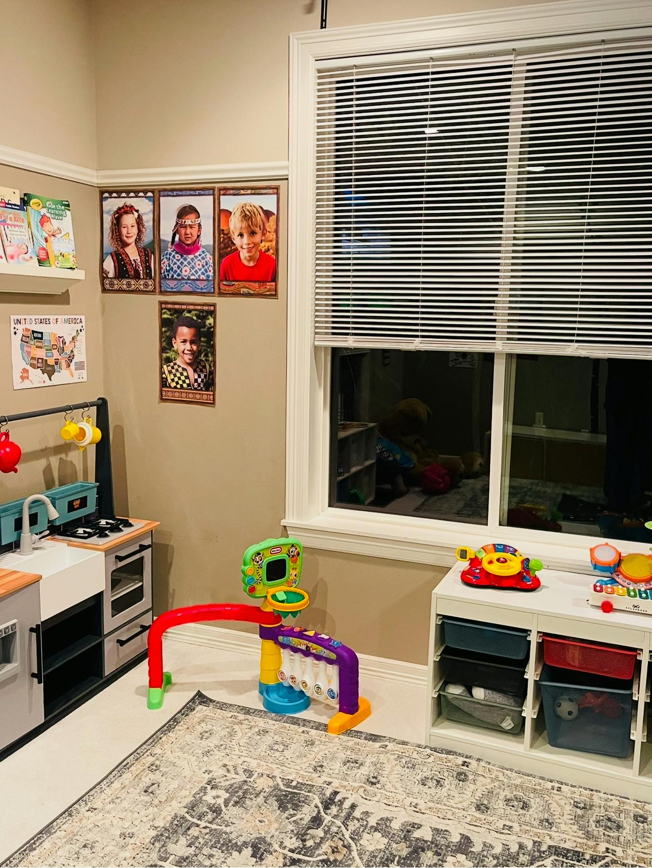 Play kitchen and colorful toys in a room with framed photos on the wall