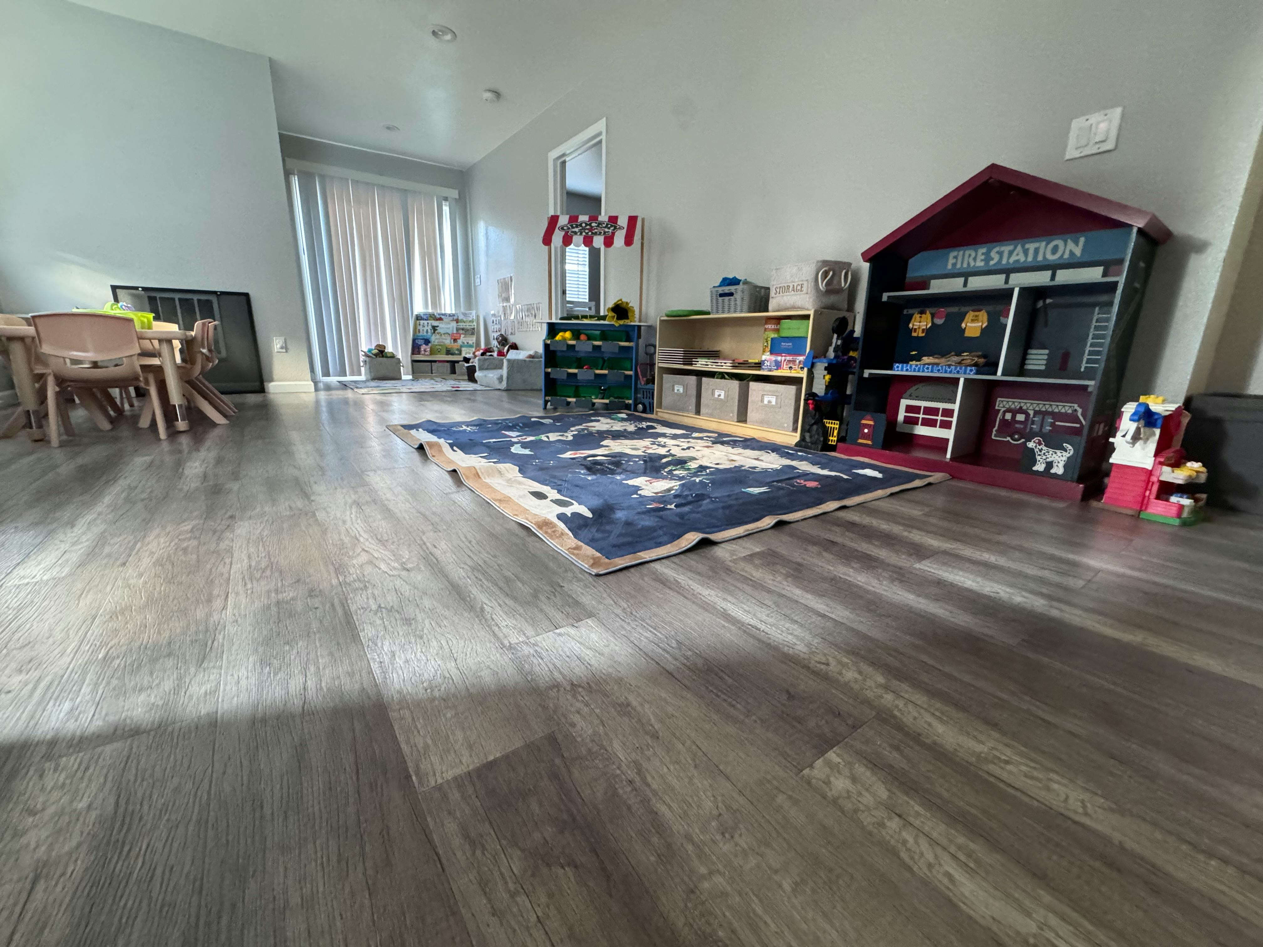 Playroom with a rug, toy fire station, and small table and chairs
