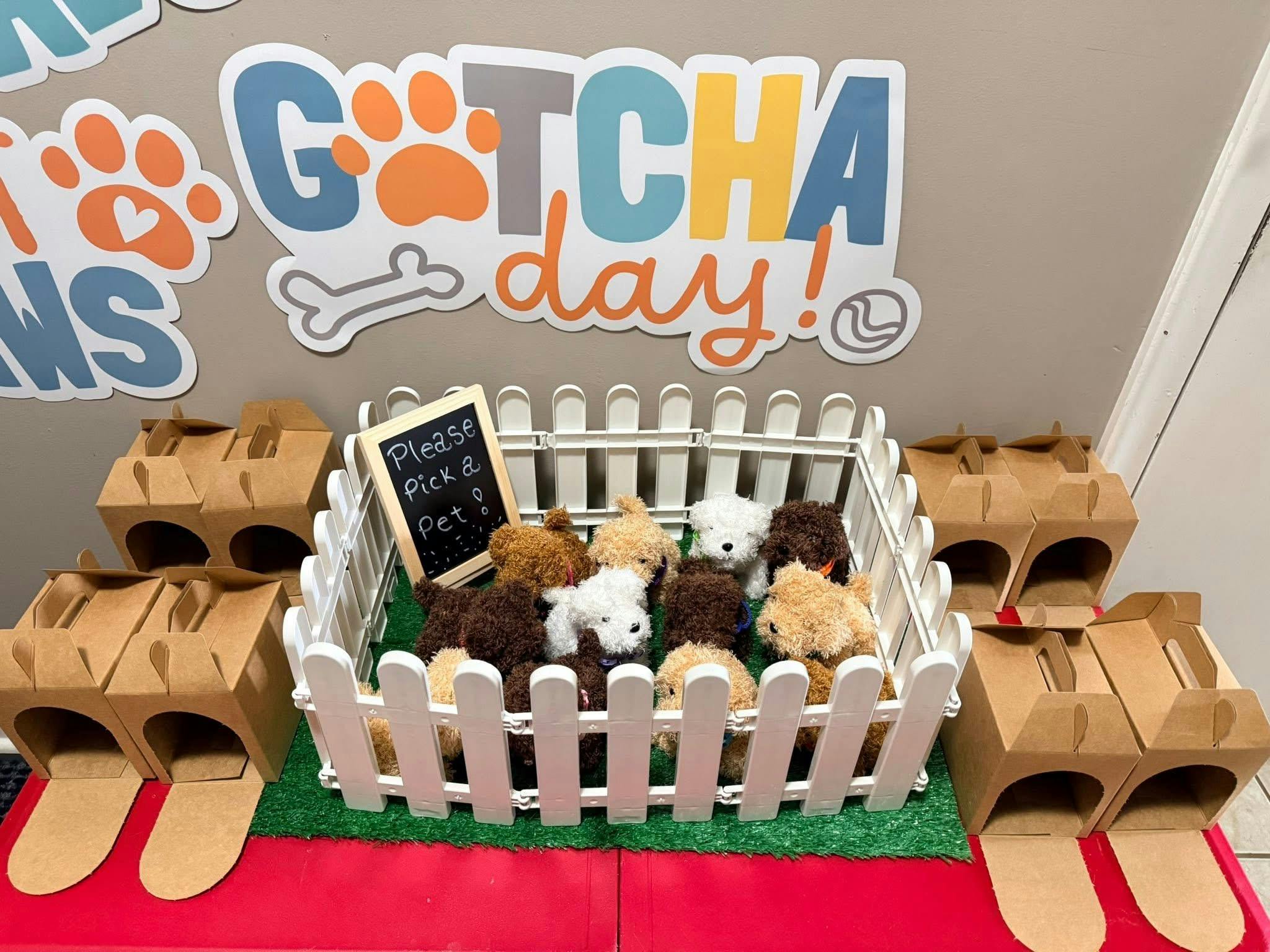 Plush puppies in a white picket fence enclosure with cardboard carriers