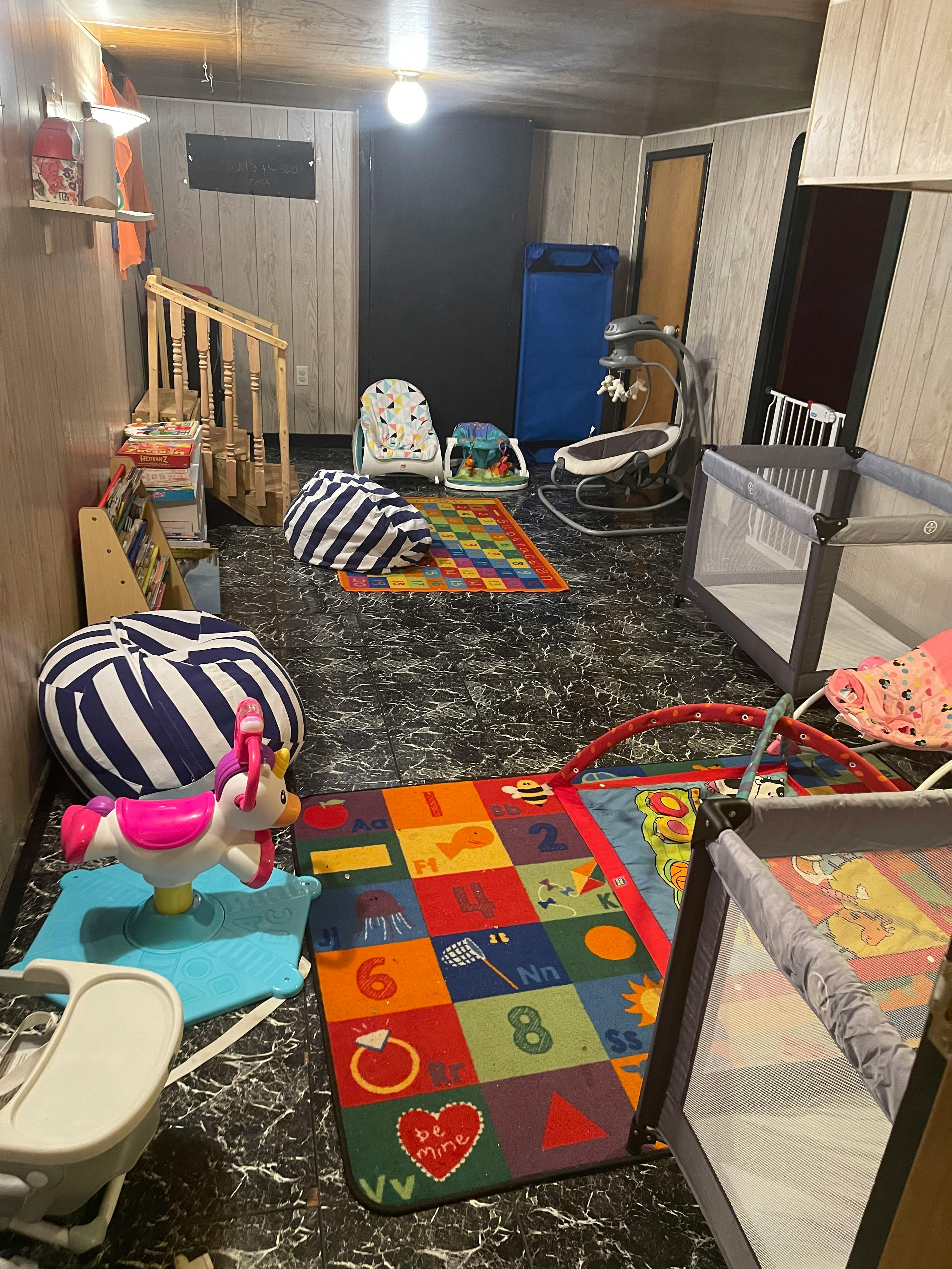 Room with baby play items including cribs, play mats, and bouncers