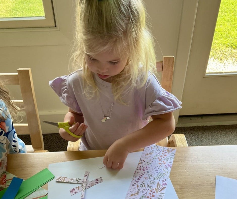Child cutting paper with scissors at a table