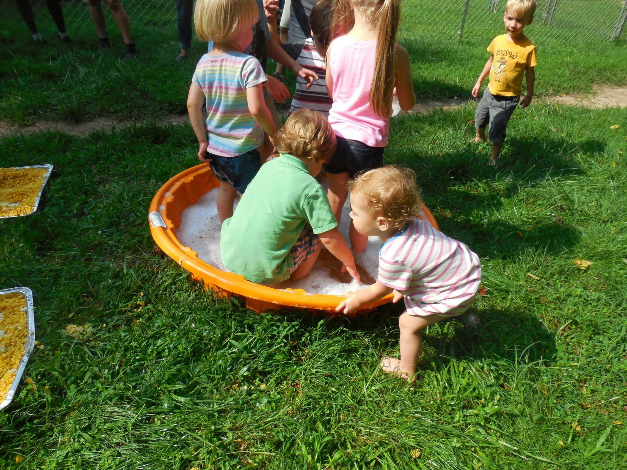 Children playing in a small inflatable pool with bubbles