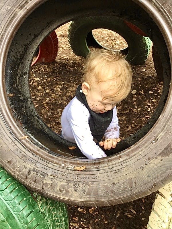 Child playing inside a tire on a playground