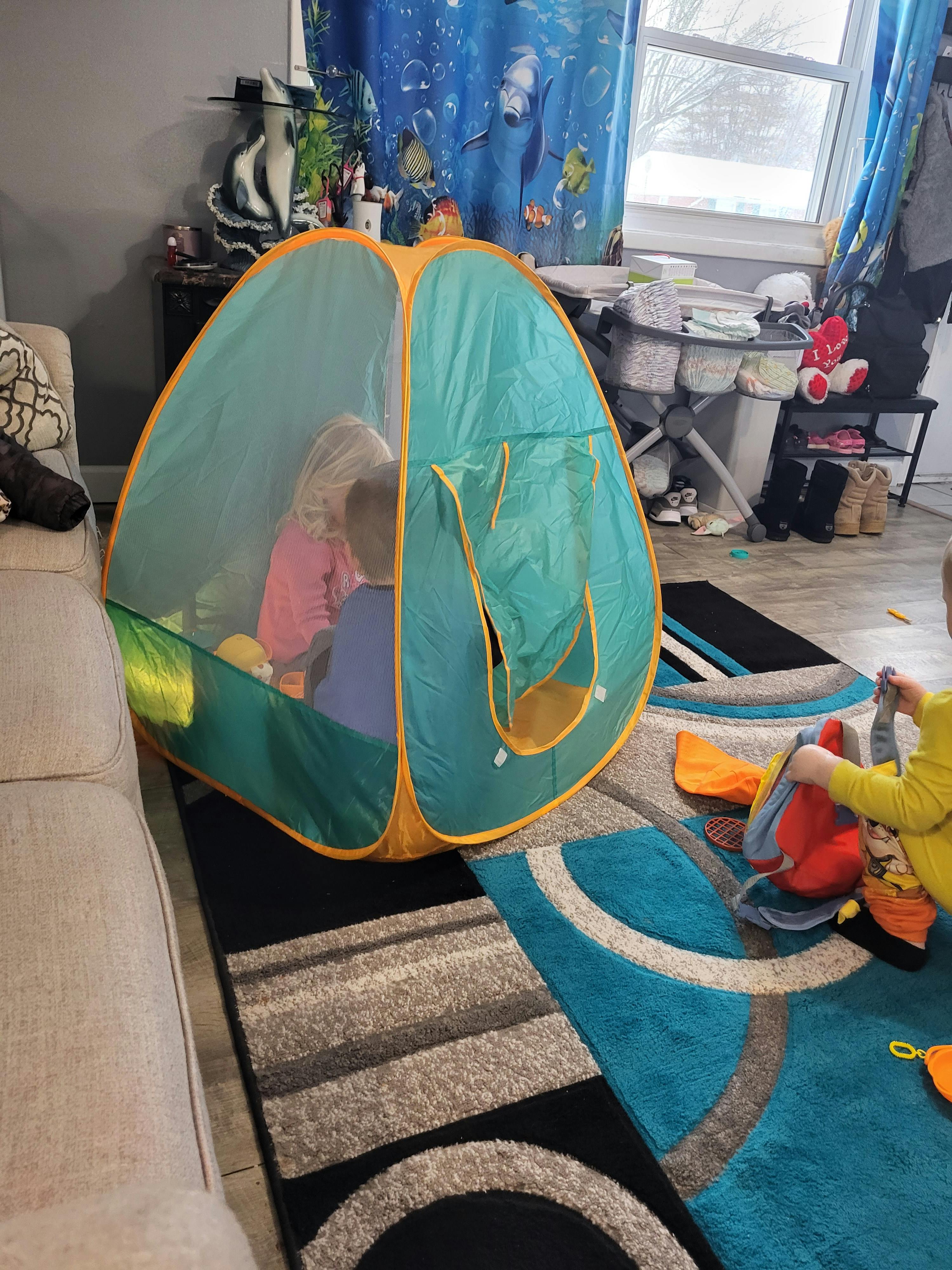 Two children playing inside a pop-up tent