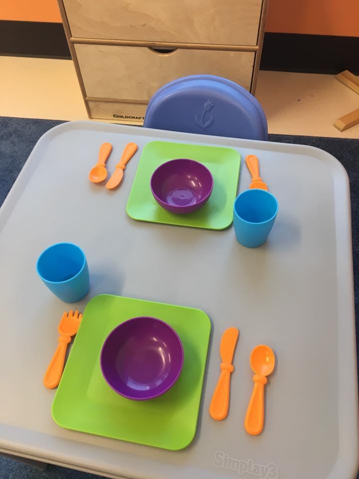 Two place settings with purple bowls, green plates, blue cups, and orange utensils