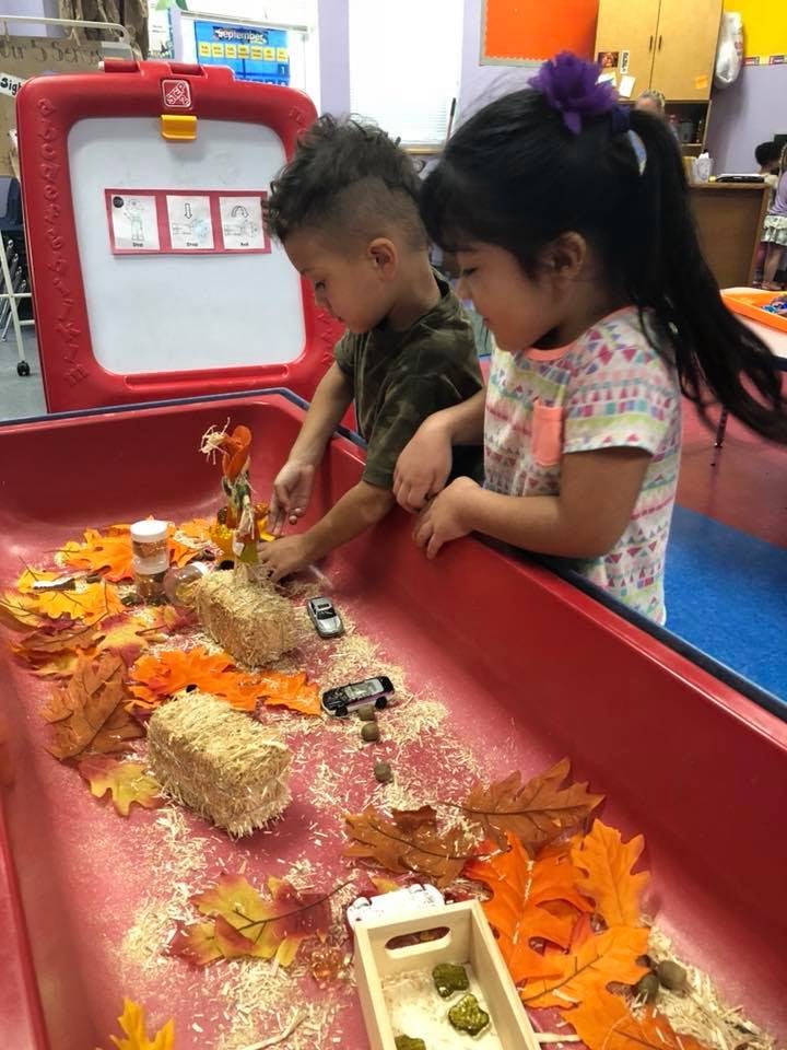Two children playing with autumn-themed sensory bin