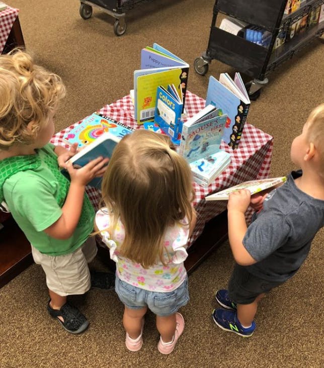 Three children looking at books on a table