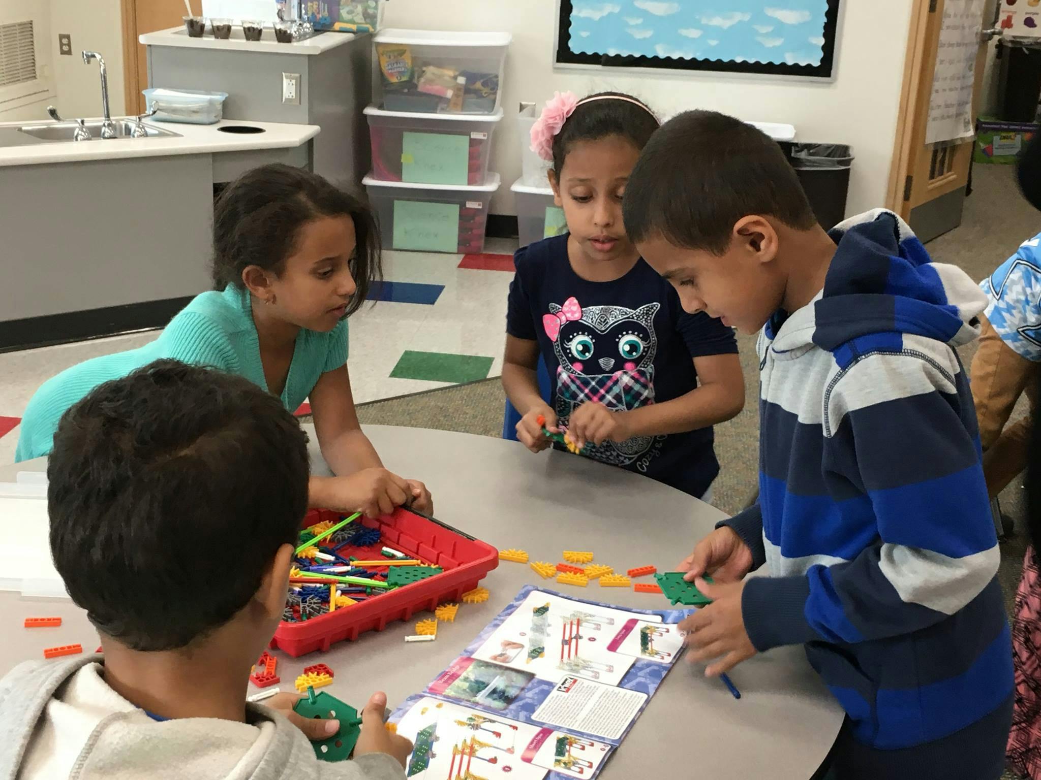 Children playing with building blocks at a table in a classroom