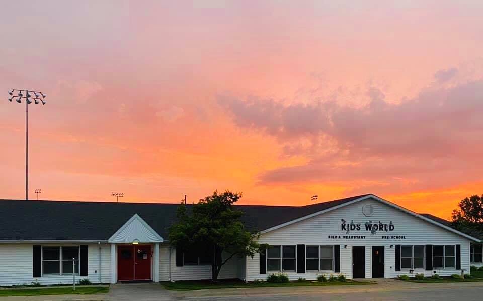 Building with "Kids World" sign under a sunset sky