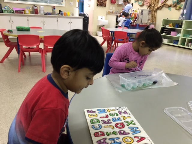 Child looking at an alphabet puzzle in a classroom
